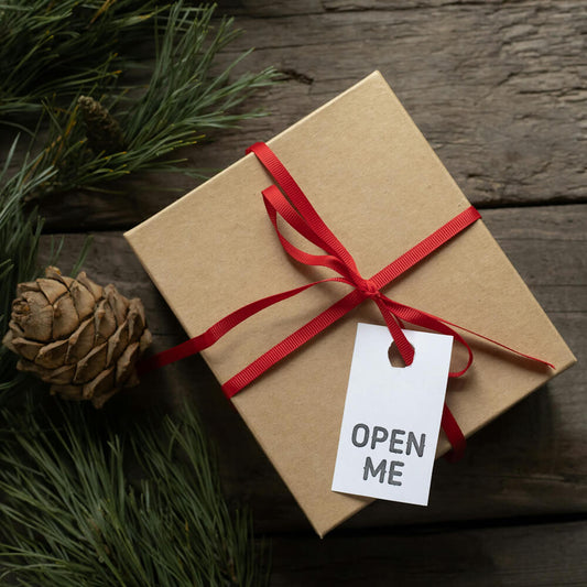 Cardboard box with "Open Me" label and red ribbon